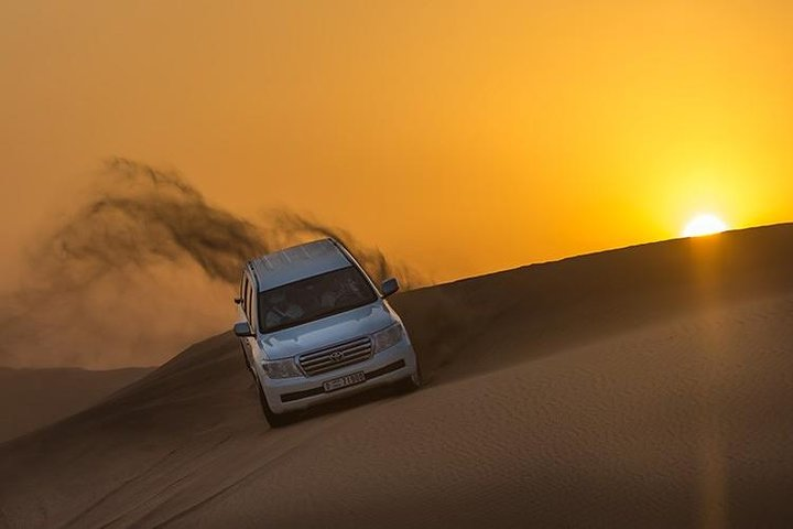 Experience the thrill of navigating endless golden dunes as the sun sets creating a breathtaking backdrop for an unforgettable adventure in the Arabian desert.